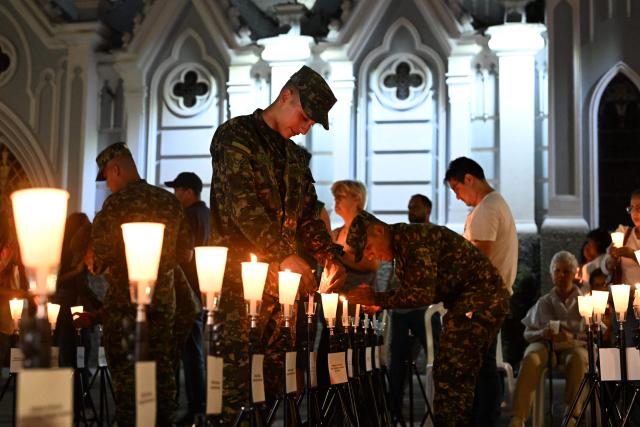 Colombian soldiers light candles during a vigil for the victims of the Colombian Air Force Hercules crash in Puerto Leguizamo, outside La Ermita church in Cali, Colombia on March 25, 2026. At least 69 soldiers and police officers were killed in one of the deadliest air accidents in Colombia's recent history, according to a new March 24 tally of the crash, which the government attributed to a ‘junk’ aircraft donated by the United States. (Photo by Joaquнn SARMIENTO / AFP)