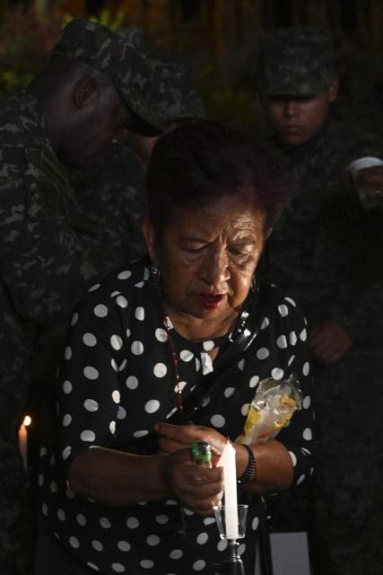 A woman lights a candle during a vigil for the victims of the Colombian Air Force Hercules crash in Puerto Leguizamo, outside La Ermita church in Cali, Colombia, on March 25, 2026. At least 69 soldiers and police officers were killed in one of the deadliest air accidents in Colombia's recent history, according to a new March 24 tally of the crash, which the government attributed to a ‘junk’ aircraft donated by the United States. (Photo by Joaquнn SARMIENTO / AFP)