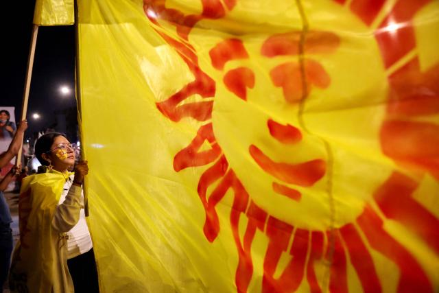A supporter of Peru's presidential candidate Jorge Nieto waves a Buen Gobierno party flag during the third round of debates on tackling crime and corruption at the Lima Convention Center in Lima on March 25, 2026. Peru will hold presidential elections on April 12. (Photo by Connie FRANCE / AFP)