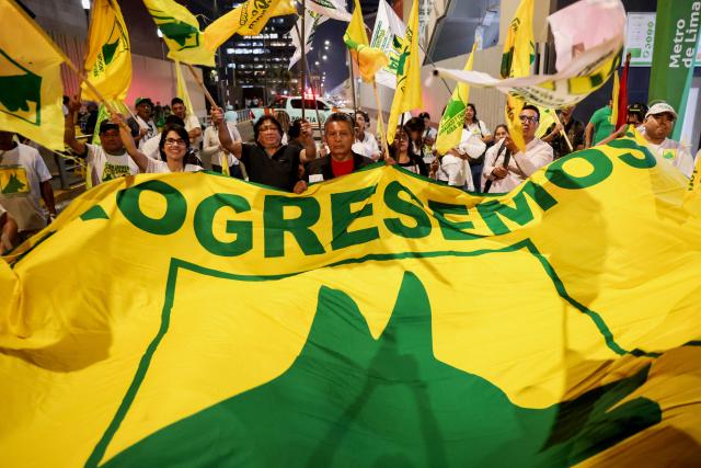 Supporters of Peru's presidential candidate Paul Jaimes wave a Progresemos party flag during the third round of debates on tackling crime and corruption at the Lima Convention Center in Lima on March 25, 2026. Peru will hold presidential elections on April 12. (Photo by Connie FRANCE / AFP)