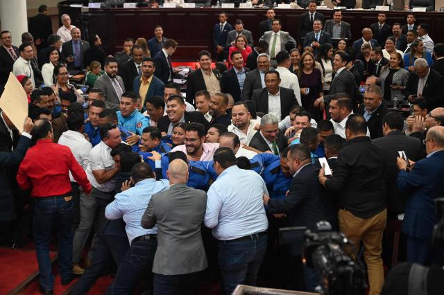 Lawmakers from the opposition Liberty and Refoundation (LIBRE) party protest against the election of Honduras’ new Attorney General, Pablo Emilio Reyes Theodore (out of frame), in Tegucigalpa on March 25, 2026. Honduras’ Congress, controlled by the right, suspended Attorney General Johel Zelaya on the night of March 23, 2026. Zelaya, who is close to the previous leftist government, was removed to face an impeachment trial on accusations of abuse of authority and persecution during last November’s elections. (Photo by Orlando SIERRA / AFP)