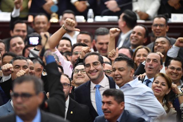 Lawmakers celebrate the election of Honduras’ new Attorney General, Pablo Emilio Reyes Theodore (out of frame), after he was sworn in in Tegucigalpa on March 25, 2026. Honduras’ Congress, controlled by the right, suspended Attorney General Johel Zelaya on the night of March 23, 2026. Zelaya, who is close to the previous leftist government, was removed to face an impeachment trial on accusations of abuse of authority and persecution during last November’s elections. (Photo by Orlando SIERRA / AFP)