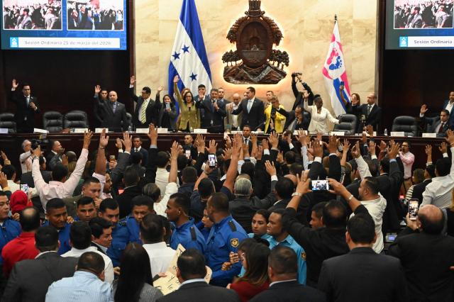 Lawmakers vote in favor of electing Honduras’ new Attorney General, Pablo Emilio Reyes Theodore (out of frame), in Tegucigalpa on March 25, 2026. Honduras’ Congress, controlled by the right, suspended Attorney General Johel Zelaya on the night of March 23, 2026. Zelaya, who is close to the previous leftist government, was removed to face an impeachment trial on accusations of abuse of authority and persecution during last November’s elections. (Photo by Orlando SIERRA / AFP)