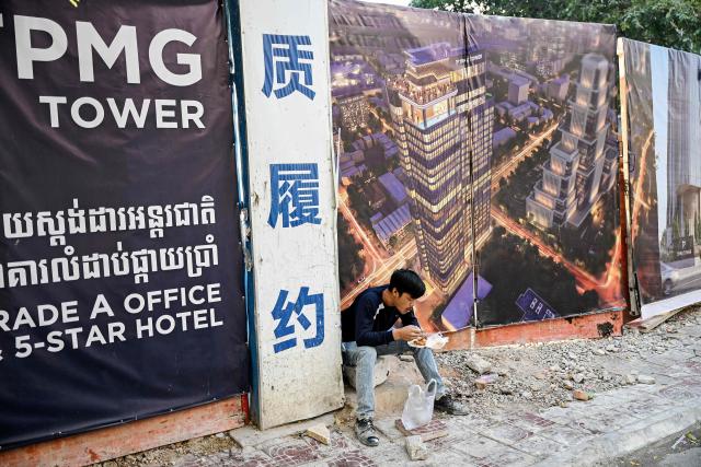 A construction worker eats breakfast on a street in Phnom Penh on March 26, 2026. (Photo by TANG CHHIN Sothy / AFP)