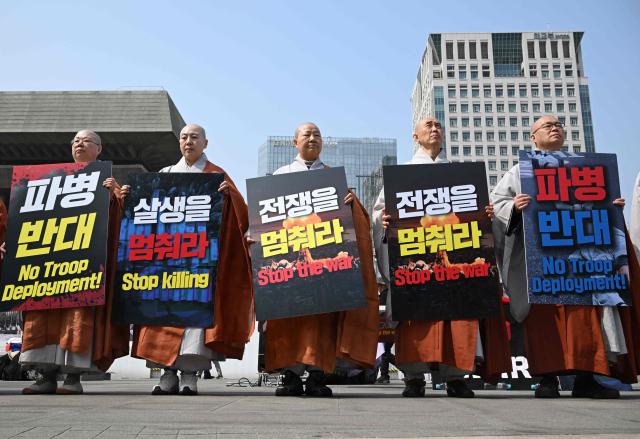 South Korean Buddhist monks hold placards reading "Stop the war" during a prayer service opposing the war on Iran in front of the US embassy in Seoul on March 26, 2026. (Photo by Jung Yeon-je / AFP)