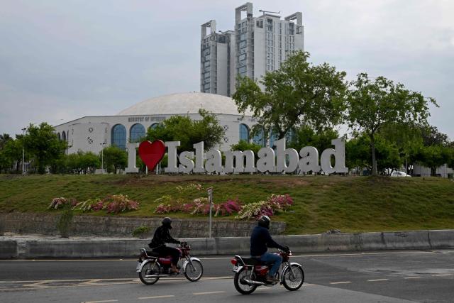 Motorcyclists ride past the Diplomatic Enclave in Islamabad on March 26, 2026. Proposals from the United States to end the war in Iran have been sent to Tehran through Pakistani intermediaries, two senior officials in Islamabad told AFP on March 25. (Photo by Aamir QURESHI / AFP)