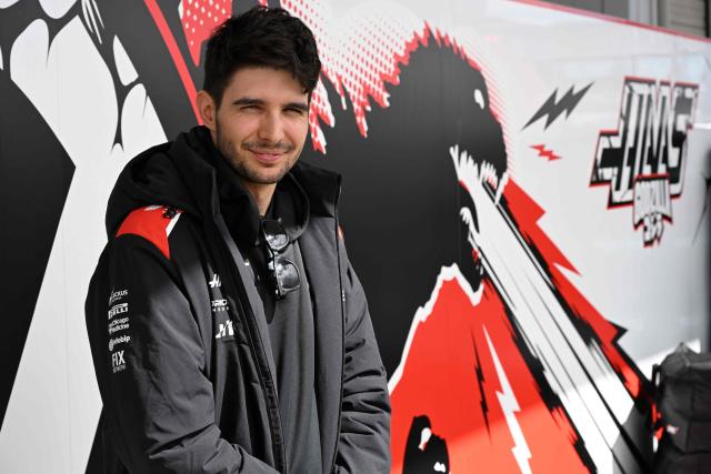 Haas F1 Team's French driver Esteban Ocon is interviewed beside his team's Japanese Grand Prix special livery of Godzilla illustration at the paddock preparing ahead of the March 29 Formula One Japanese Grand Prix race at the Suzuka circuit in Suzuka, Mie prefecture on March 26, 2026. (Photo by Toshifumi KITAMURA / AFP)