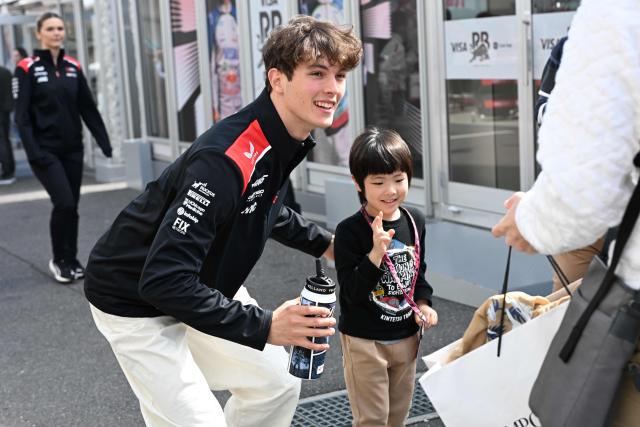Haas F1 Team's British driver Oliver Bearman (L) poses for a picture with a young F1 fan preparing for the March 29 Formula One Japanese Grand Prix race at the Suzuka circuit in Suzuka, Mie prefecture on March 26, 2026. (Photo by Toshifumi KITAMURA / AFP)