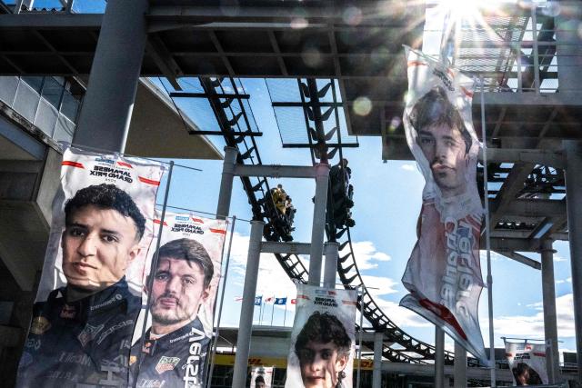 TOPSHOT - Fans ride on a roller-coaster as banners of drivers are seen ahead of the Formula One Japanese Grand Prix in Suzuka on March 26, 2026. (Photo by Philip FONG / AFP)