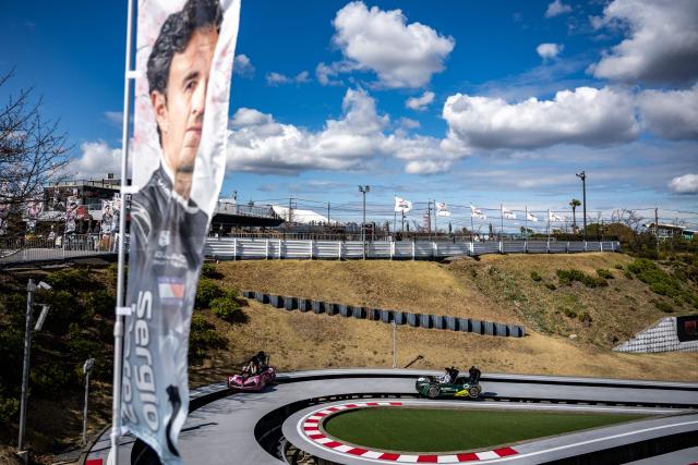 Fans ride karts past a banner of Cadillac's Mexican driver Sergio Perez ahead of the Formula One Japanese Grand Prix in Suzuka on March 26, 2026. (Photo by Philip FONG / AFP)
