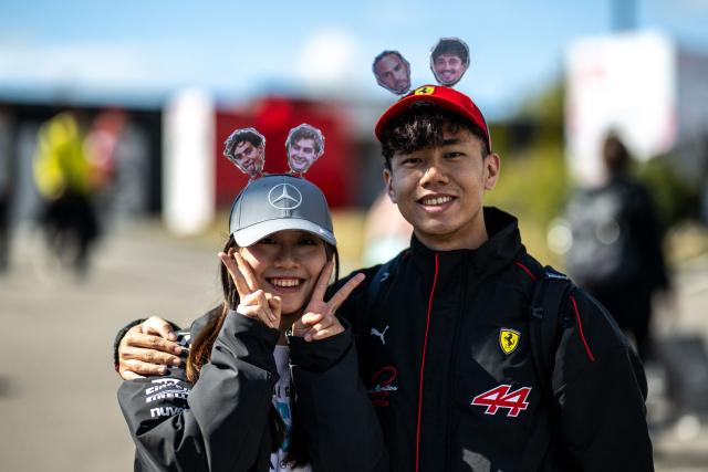 Fans wear decorative hats with the portraits of their supporting drivers ahead of the Formula One Japanese Grand Prix in Suzuka on March 26, 2026. (Photo by Philip FONG / AFP)