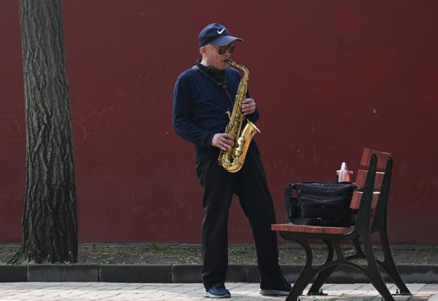 A man plays the axophone outside of the Jingshan park in Beijing on March 26, 2026. (Photo by ADEK BERRY / AFP)