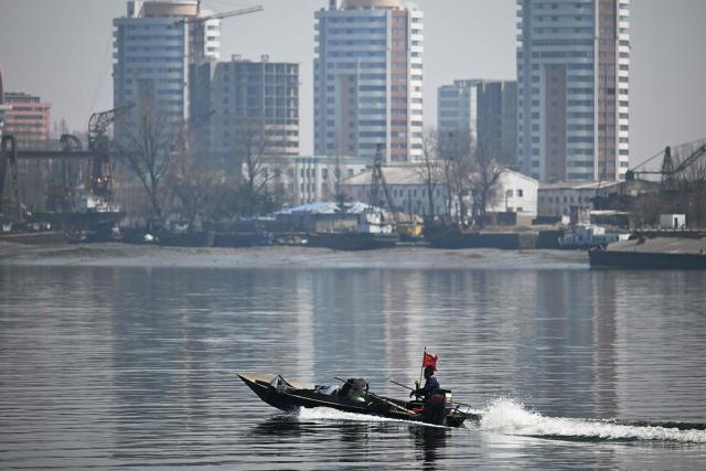 A Chinese boat cruises on the Yalu River as the North Korean town of Sinuiju is seen behind, opposite the border city of Dandong, in China's northeast Liaoning province on March 26, 2026. Passenger rail travel between China and North Korea resumed on March 12, after a pause of more than six years triggered by the COVID-19 outbreak. (Photo by GREG BAKER / AFP)