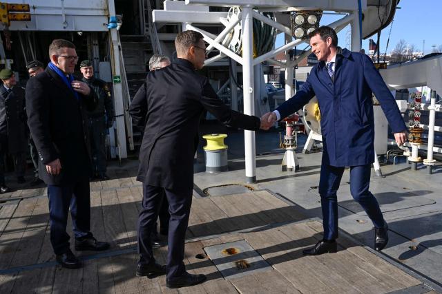 Estonian Prime Minister Kristen Michal (L) looks on as Finnish President Alexander Stubb (C) greets Danish Permanent Under-Secretary of State for Foreign Affairs Anders Tang Friborg (R) onboard the Finnish Border Guard offshore patrol vessel Turva prior the Joint Expeditionary Force JEF Leaders’ Summit in Helsinki, Finland on March 26, 2026. The topics on the agenda include support from the JEF countries to Ukraine and the overall security situation in Europe. (Photo by Heikki Saukkomaa / Lehtikuva / AFP) / Finland OUT