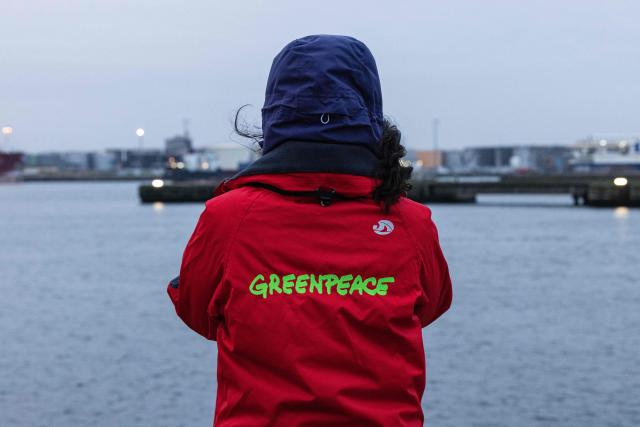(FILES) A Greenpeace activist observes the arrival of the Russian cargo ship, the Baltiyskiy 202, loaded with several cylinders of uranium from Russia at the port of Dunkirk, northern France on March 20, 2023. Faced with a decline in donations, the environmental charity Greenpeace France announced on March 26, 2026 that it would have to reduce its workforce by around a quarter, from the current 138 full-time equivalents to 106. (Photo by Sameer Al-DOUMY / AFP)
