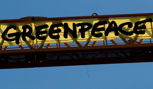 (FILES) Greenpeace activists hang, on a crane, a giant banner reading "Greenpeace" during a protest against the French government's politics on environment, on the work site of Notre-Dame Cathedral, in Paris, on July 9, 2020. Faced with a decline in donations, the environmental charity Greenpeace France announced on March 26, 2026 that it would have to reduce its workforce by around a quarter, from the current 138 full-time equivalents to 106. (Photo by GEOFFROY VAN DER HASSELT / AFP)
