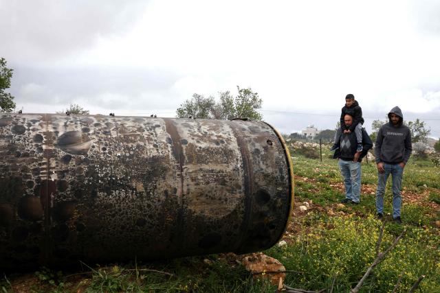 Palestinian residents inspect the remnants of an missile that landed in the Israeli-occupied West Bank village of Beitin, northeast of the city of Ramallah on March 26, 2026. On February 28, Israel and the United States launched strikes on Iran killing its supreme leader and triggering a war that spread across the Middle East and unleashed chaos across global markets. (Photo by Zain JAAFAR / AFP) / 
