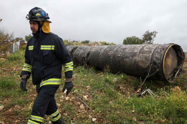 A Palestinian officer walks away after inspecting the remnants of an missile that landed in the Israeli-occupied West Bank village of Beitin, northeast of the city of Ramallah on March 26, 2026. On February 28, Israel and the United States launched strikes on Iran killing its supreme leader and triggering a war that spread across the Middle East and unleashed chaos across global markets. (Photo by Zain JAAFAR / AFP) / 