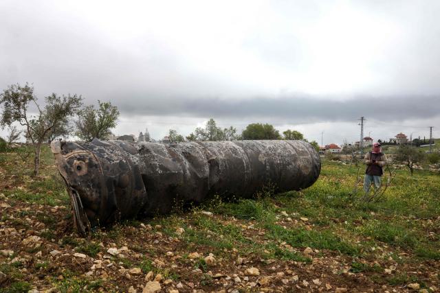 A Palestinian man inspect the remnants of an missile that landed in the Israeli-occupied West Bank village of Beitin, northeast of the city of Ramallah on March 26, 2026. On February 28, Israel and the United States launched strikes on Iran killing its supreme leader and triggering a war that spread across the Middle East and unleashed chaos across global markets. (Photo by Zain JAAFAR / AFP) / 