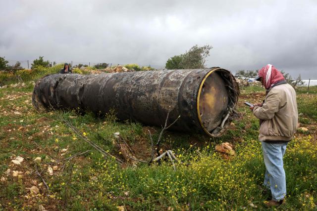 Palestinian men inspect the remnants of a missile that landed in the Israeli-occupied West Bank village of Beitin, northeast of the city of Ramallah, on March 26, 2026. On February 28, Israel and the United States launched strikes on Iran killing its supreme leader and triggering a war that spread across the Middle East and unleashed chaos across global markets. (Photo by Zain JAAFAR / AFP) / 