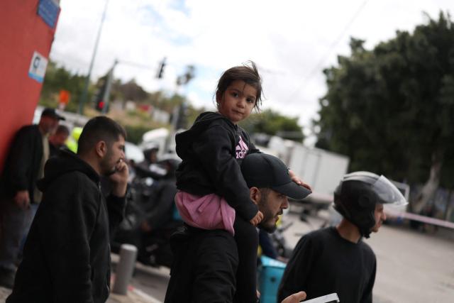 Residents look on following a projectile strike on south Tel Aviv on March 26, 2026. The Middle East was sparked by joint US-Israeli strikes on Iran that triggered a wave of retaliatory missile and drone attacks against Israel and several other countries in the region. (Photo by Ilia YEFIMOVICH / AFP) / 