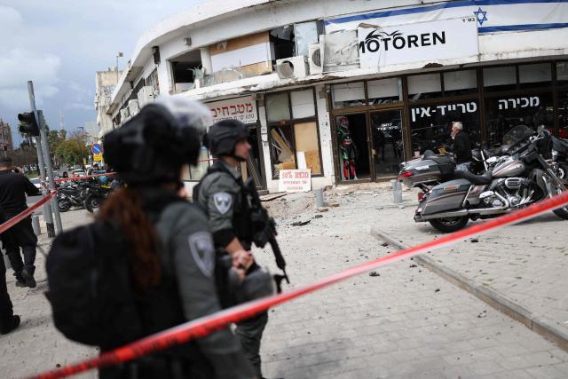 TOPSHOT - Israeli security forces cordon off the area following a projectile strike on south Tel Aviv on March 26, 2026. The Middle East was sparked by joint US-Israeli strikes on Iran that triggered a wave of retaliatory missile and drone attacks against Israel and several other countries in the region. (Photo by Ilia YEFIMOVICH / AFP) / 