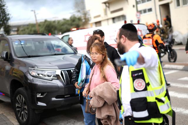 Residents are directed away as they stop to look at the damage following a projectile strike on south Tel Aviv on March 26, 2026. The Middle East was sparked by joint US-Israeli strikes on Iran that triggered a wave of retaliatory missile and drone attacks against Israel and several other countries in the region. (Photo by Ilia YEFIMOVICH / AFP) / 