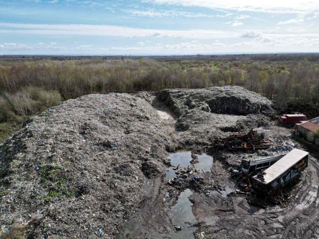 This aerial view shows an illegal rubbish dump, estimated to contain 25,000 tonnes of waste and which is due to be cleared by the Environment Agency, in Bickershaw, near Wigan in north-west England on March 26, 2026. Waste has been deposited on the site, which is partly owned by several parties, including Wigan Council and the Duchy of Lancaster, since October 2024. (Photo by Oli SCARFF / AFP)