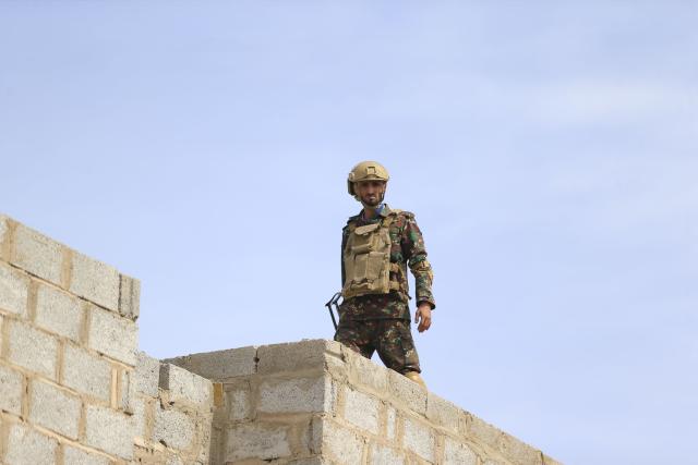 A Yemeni soldier stands guard on the roof of a building while supporters of Yemen's Huthi movement attend an event commemorating the ninth anniversary of the Saudi-led intervention in their country, in the capital Sanaa on March 26, 2026. (Photo by Mohammed HUWAIS / AFP)