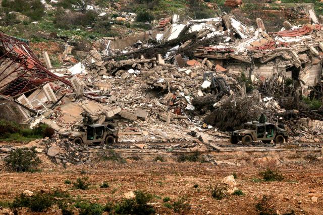 Israeli military vehicles move past destroyed buildings in southern Lebanon close to the Israeli border on March 26, 2026. Lebanon was drawn into the Middle East war on March 2, when pro-Iran Hezbollah launched rockets towards Israel in response to US-Israeli strikes that killed Iranian supreme leader on February 28. (Photo by Jack GUEZ / AFP) / 
