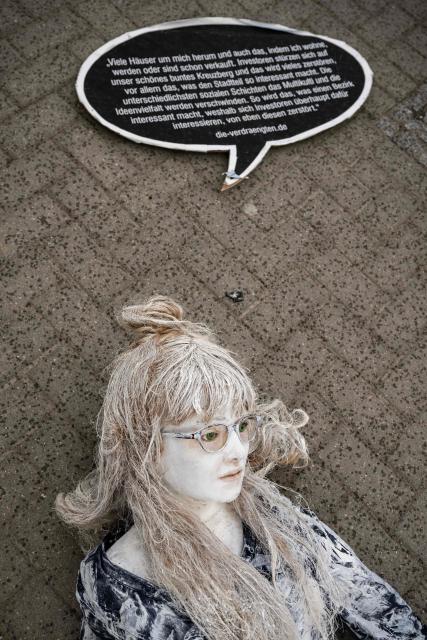 A mannequin representing a homeless woman lies on the pavement before being placed in front of the Berlin Town Hall (Rotes Rathaus) during a demonstration to call attention to the plight of homeless and evicted persons in the German capital, on March 26, 2026. The placard recounts the experience of a homeless person gathered by the website die-verdraengten.de. (Photo by John MACDOUGALL / AFP)