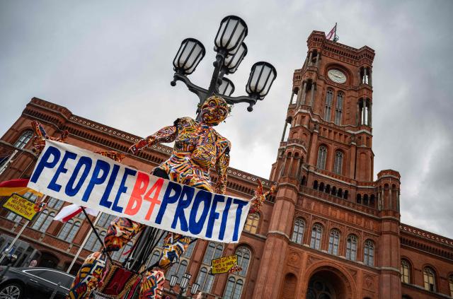 A giant figure hangs from a lamppost in front of the Berlin Town Hall (Rotes Rathaus) during a demonstration to call attention to the plight of homeless and evicted persons in the German capital, on March 26, 2026. The placard recounts the experience of a homeless person gathered by the website die-verdraengten.de. (Photo by John MACDOUGALL / AFP)