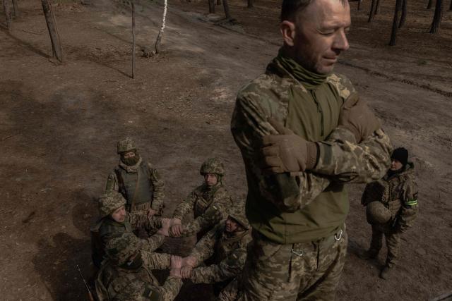 A Ukrainian recruit falls as his fellow soldiers prepare to catch him during a basic military training at the Ukrainian Ground Forces training center, in an undisclosed location on March 25, 2026, amid the Russian invasion of Ukraine. (Photo by Roman PILIPEY / AFP)