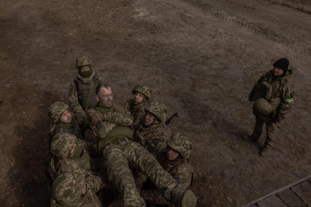 A Ukrainian recruit falls as fellow soldiers catch him during a basic military training at the Ukrainian Ground Forces training center, in an undisclosed location on March 25, 2026, amid the Russian invasion of Ukraine. (Photo by Roman PILIPEY / AFP)