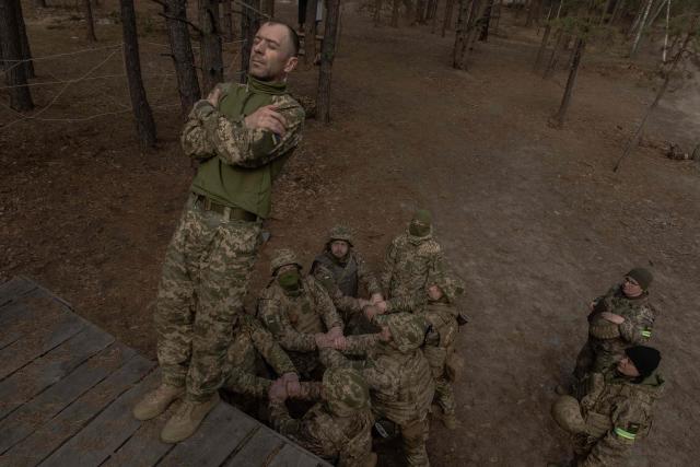 A Ukrainian recruit falls as his fellow soldiers prepare to catch him during a basic military training at the Ukrainian Ground Forces training center, in an undisclosed location on March 25, 2026, amid the Russian invasion of Ukraine. (Photo by Roman PILIPEY / AFP)