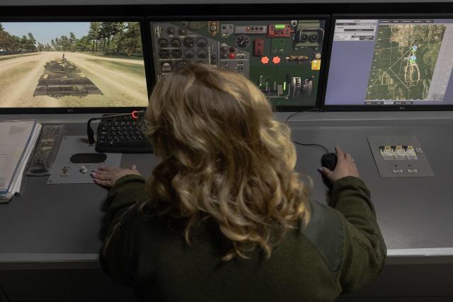 A Ukrainian military member looks at screens as a Ukrainian serviceman practices his driving skills on an armoured vehicle simulator at the Ukrainian Ground Forces training center in an undisclosed location on March 25, 2026, amid the Russian invasion of Ukraine. (Photo by Roman PILIPEY / AFP)