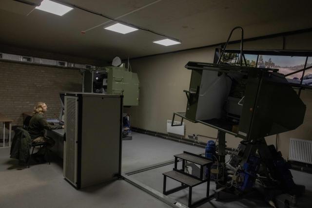 A Ukrainian military member looks at screens as a Ukrainian serviceman practices his driving skills on an armoured vehicle simulator at the Ukrainian Ground Forces training center in an undisclosed location on March 25, 2026, amid the Russian invasion of Ukraine. (Photo by Roman PILIPEY / AFP)