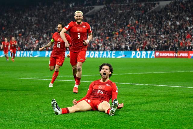 Turkey's defender #20 Ferdi Kadioglu (down) celebrates after scoring his team first goal during the play-off FIFA World Cup 2026 European qualification knockout semi-final football match between Turkey and Romania at Besiktas Park stadium, in Istanbul on March 26, 2026. (Photo by YASIN AKGUL / AFP)