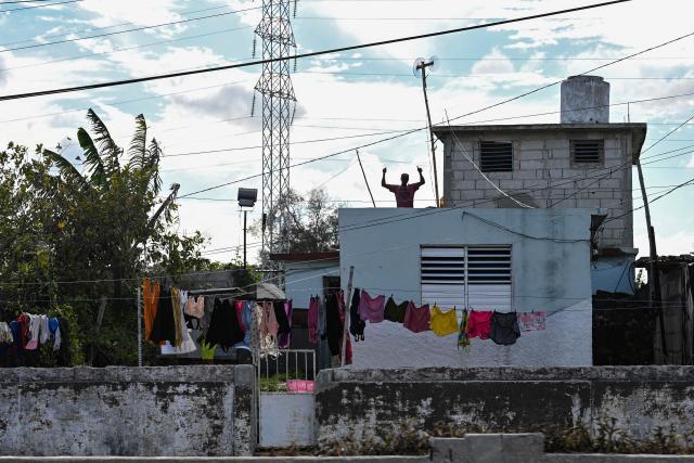 A man gives the thumbs up from the roof of his home next to clothes hanged to dry in Havana, on March 24, 2026. (Photo by Yuri CORTEZ / AFP)