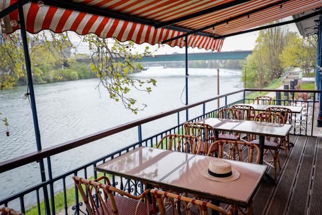 This photograph shows a boater hat displayed on the terrace where French impressionist Pierre-Auguste Renoir (1841-1919) created his painting "Luncheon of the Boating Party" (Le Dejeuner des Canotiers) at the Fournaise Museum on the Ile des Impressionnistes in Chatou, northwest Paris, on March 26, 2026. (Photo by STEPHANE DE SAKUTIN / AFP)