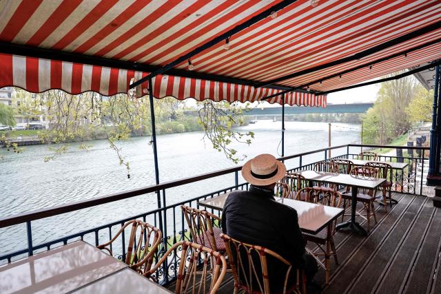 This photograph shows a man wearing a boater hat on the terrace where French impressionist Pierre-Auguste Renoir (1841-1919) created his painting "Luncheon of the Boating Party" (Le Dejeuner des Canotiers) at the Fournaise Museum on the Ile des Impressionnistes in Chatou, northwest Paris, on March 26, 2026. (Photo by STEPHANE DE SAKUTIN / AFP)