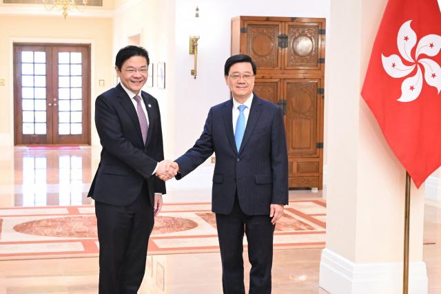 Hong Kong Chief Executive John Lee (R) and Singapore's Prime Minister Lawrence Wong (L) shake hands at Government House in Hong Kong on March 27, 2026. (Photo by Peter PARKS / POOL / AFP)