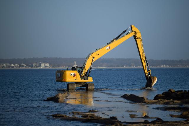An excavator is seen on the beach in Niendorf, northern Germany, on March 27, 2026, near the spot where a humpback whale had been stranded in shallow water off the Baltic Sea coast before the animal apparently freed itself overnight following a large-scale rescue operation. The humpback whale that had been stranded for several days on Germany’s Baltic coast freed itself and was able to return to the sea, but still has a long way to go before it can reach its natural habitat, a scientist told the media on site. (Photo by DANIEL REINHARDT / AFP)