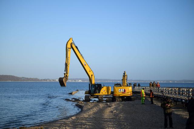 Excavators are seen on the beach in Niendorf, northern Germany, on March 27, 2026, near the spot where a humpback whale had been stranded in shallow water off the Baltic Sea coast before the animal apparently freed itself overnight following a large-scale rescue operation. The humpback whale that had been stranded for several days on Germany’s Baltic coast freed itself and was able to return to the sea, but still has a long way to go before it can reach its natural habitat, a scientist told the media on site. (Photo by DANIEL REINHARDT / AFP)