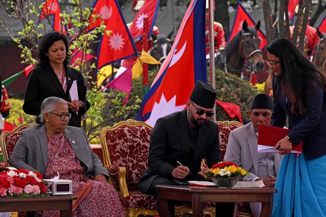 Nepal's newly sworn-in prime minister Balendra Shah (C) signs after taking oath as former interim prime minister Sushila Karki (L) looks on during a swearing-in ceremony in Kathmandu on March 27, 2026. Nepal's rapper-turned-politician Balendra Shah was sworn in as prime minister on March 27 after sweeping the first election since deadly anti-corruption protests toppled the government last year. (Photo by PRAKASH MATHEMA / AFP)