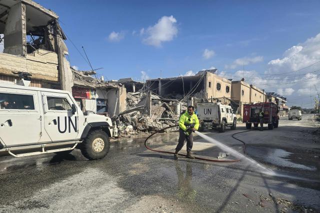 United Nations peacekeepers with the UN Interim Force in Lebanon (UNIFIL) drive past firefighters clearing the road at the site of an overninght Israeli airstrike in the area of Naqura in southern Lebanon on March 27, 2026. Lebanon was drawn into the Middle East war on March 2 when Tehran-backed Hezbollah began firing rockets into Israel to avenge the killing of the Iranian supreme leader. Israel has since been bombing Lebanon, mainly in areas where Hezbollah has long held sway, and has sent in ground troops in a push to establish a buffer zone in south Lebanon. (Photo by KAWNAT HAJU / AFP)