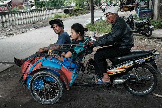 A motorcycle converted into a tricycle carries passengers in Jakarta on March 26, 2026. (Photo by YASUYOSHI CHIBA / AFP)