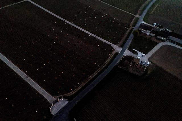 This aerial photograph shows anti-frost candles displayed in a vineyard to keep temperatures above zero degrees celsius and prevent vines from freezing, in Saint-Emilion, south-western France on March 27, 2026, as a cold wave hits the region. The announced frost episode during the night pushed winegrowers to take measures to protect their vines. (Photo by Christophe ARCHAMBAULT / AFP)
