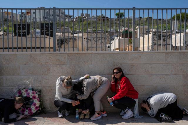 (FILES) People take cover as a war siren blasts during the funeral of Sarah and Ronit Elimelech, who were killed the previous day in an Iranian missile attack, in Bet Shemesh on March 2, 2026. The United States and Israel began the war on February 28, 2026, by attacking Iran and killing its supreme leader. Iran retaliated with strikes against Israel and US allies and interests across the Gulf and Iraq, drawing the whole region into war. (Photo by Maya Levin / AFP)
