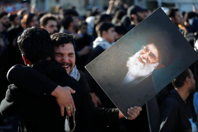 (FILES) Iraqi Shiites Muslim men grieve as one holds up the image of killed Iranian supreme leader Ayatollah Ali Khamenei, during a symbolic funeral the day after his assassination, in the district of Sadr City, in Baghdad on March 1, 2026. The United States and Israel began the war on February 28, 2026, by attacking Iran and killing its supreme leader. Iran retaliated with strikes against Israel and US allies and interests across the Gulf and Iraq, drawing the whole region into war. (Photo by AHMAD AL-RUBAYE / AFP)